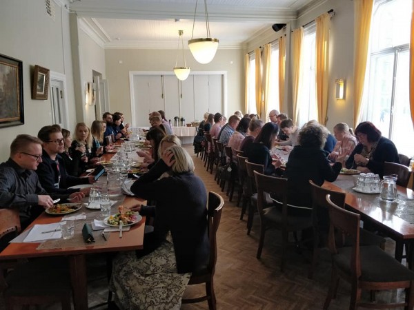 Kuva kertoo, että tila on täynnä ihmisiä, ja täyttää hyvin sen tehtävän. Koska useimmat ihmiset ovat kuvassa selin tai näkyvät sivusta päin, henkilöt jäävät katsojalle aika etäisiksi ja kuvan tunnelma on vaisu. Tämä on kuitenkin aika tyypillinen kuva seminaaritilanteesta.